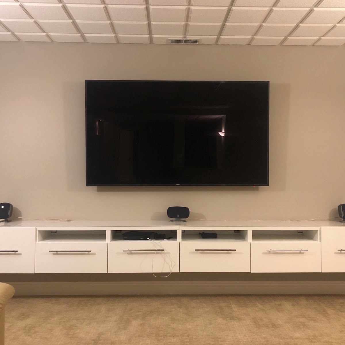 Surround sound speakers integrated into a media console beneath a wall-mounted TV