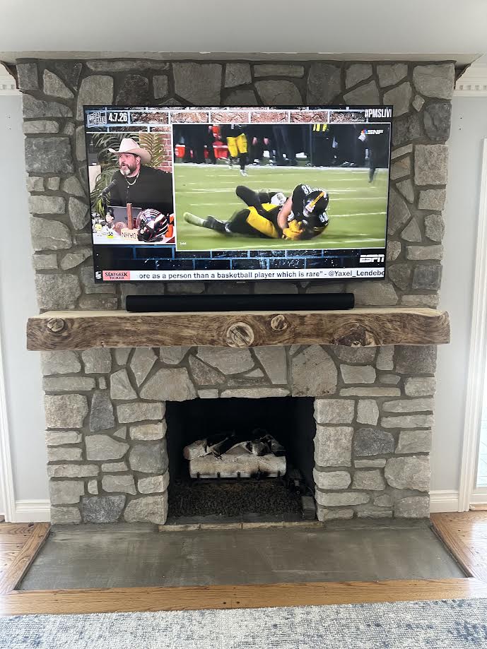 TV mounted above a stone fireplace by Rtechwork for a Metro Detroit area home